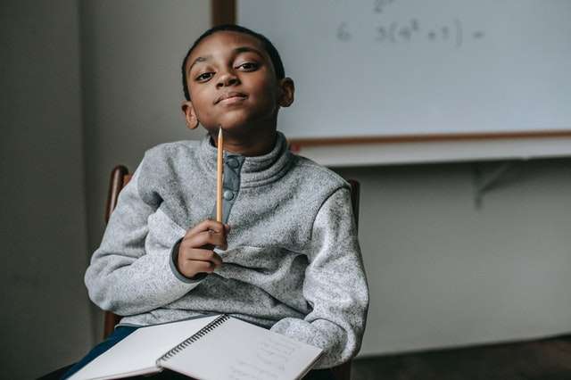 Young African American student with pencil in hand, thinking in a classroom setting.
