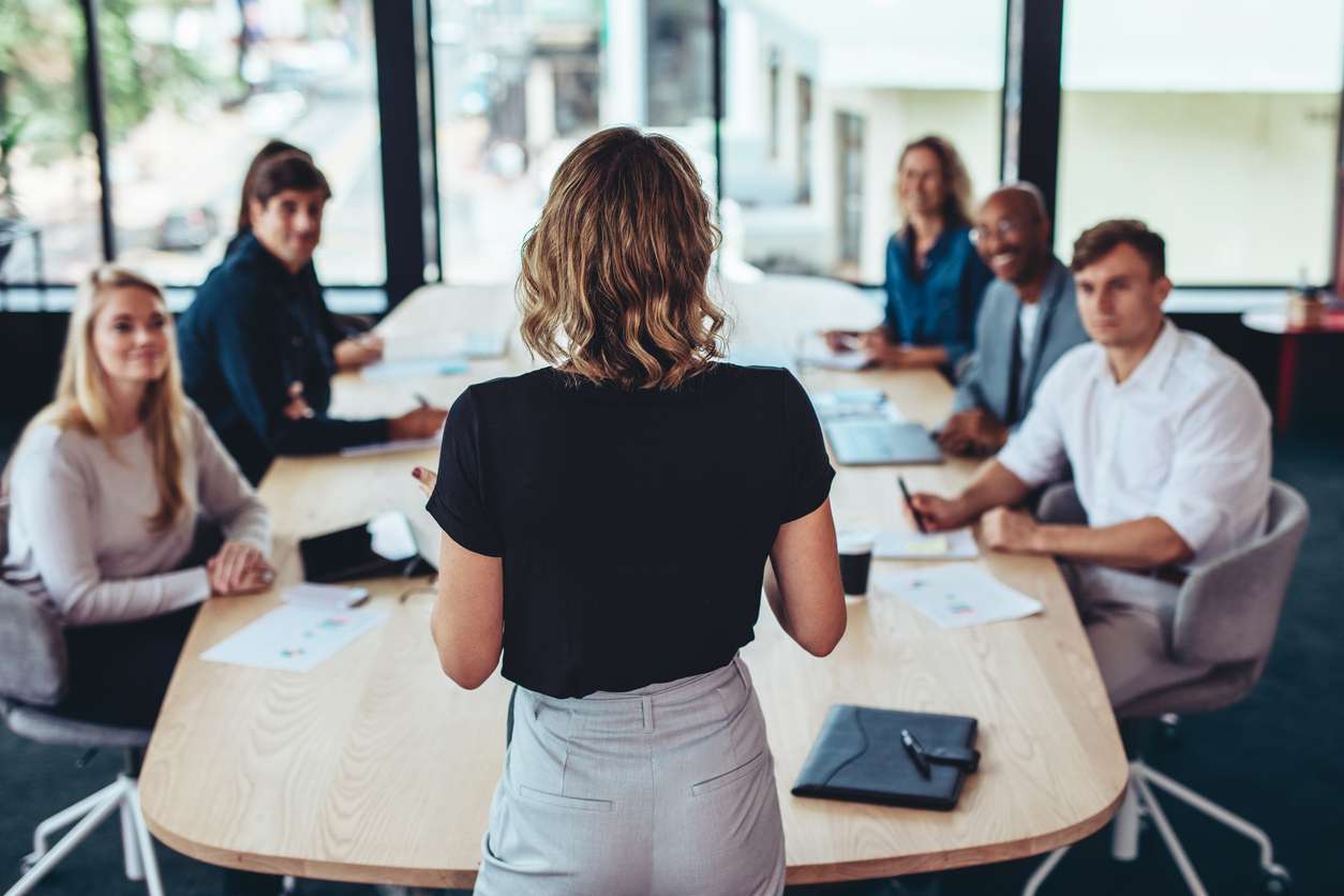 Businesswoman addressing a meeting in office with the leaders and other memebers