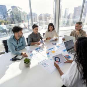 Multi racial group of people working with Paperwork on a board room table at a business presentation or seminar.