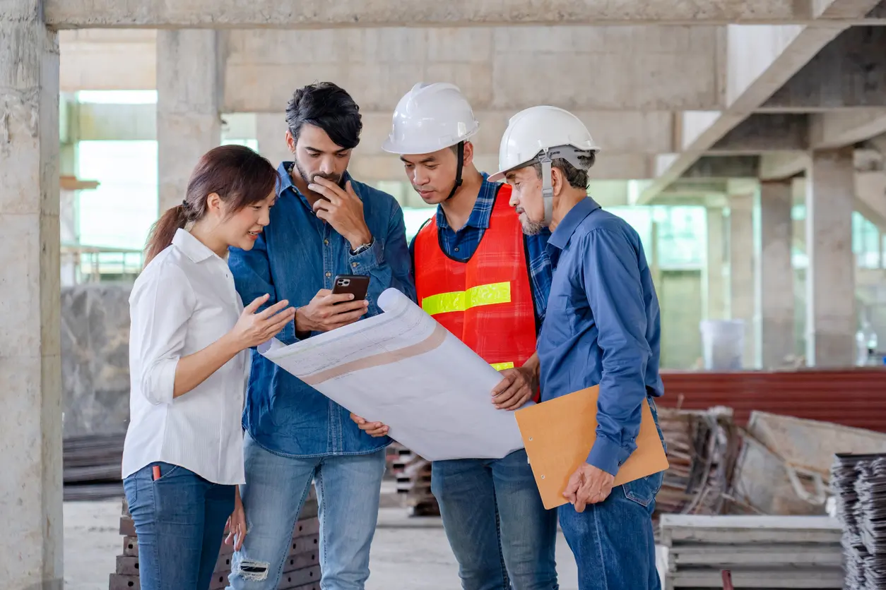 Construction team reviewing blueprints on a job site visit