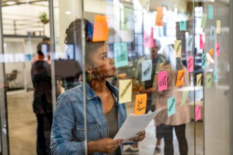 Portrait of a thoughtful business woman using adhesive notes while brainstorming at a creative office