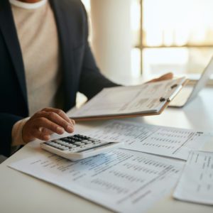 Close up of African American entrepreneur going through business budget and using calculator in the office