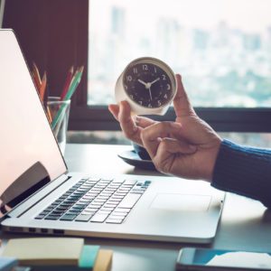 Business concepts with businessman holding clock on computer laptop.For investment analysis,Waiting to sucess