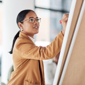 Creative woman, meeting and writing on Flipchart for team building, coaching or activity ideas at office.