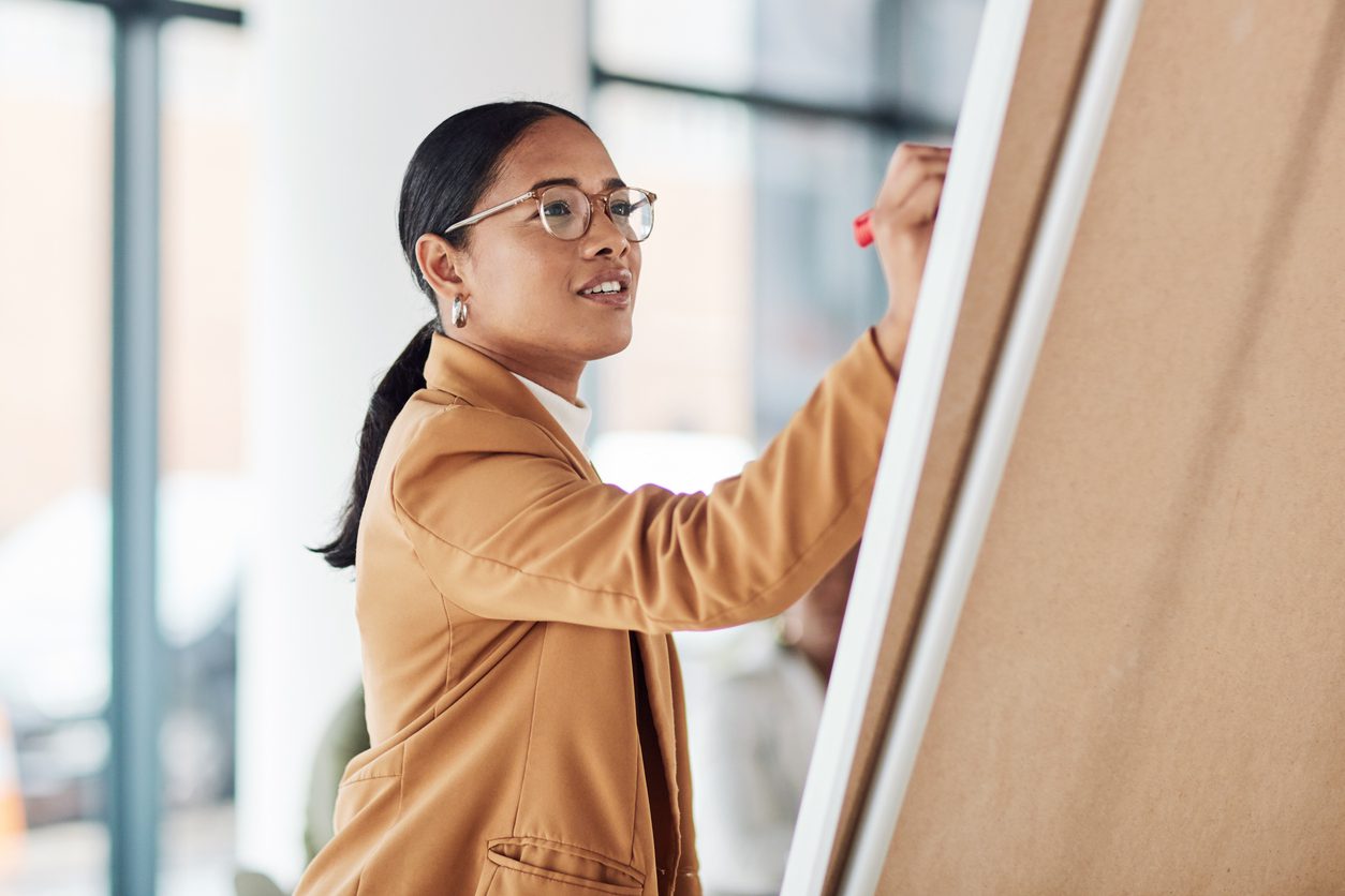 Creative woman, meeting and writing on Flipchart for team building, coaching or activity ideas at office.