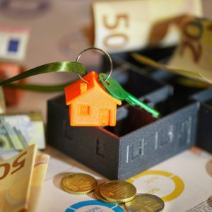 Money and a house key over financial charts, symbolizing school facilities planning and budget management