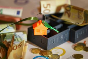 Money and a house key over financial charts, symbolizing school facilities planning and budget management
