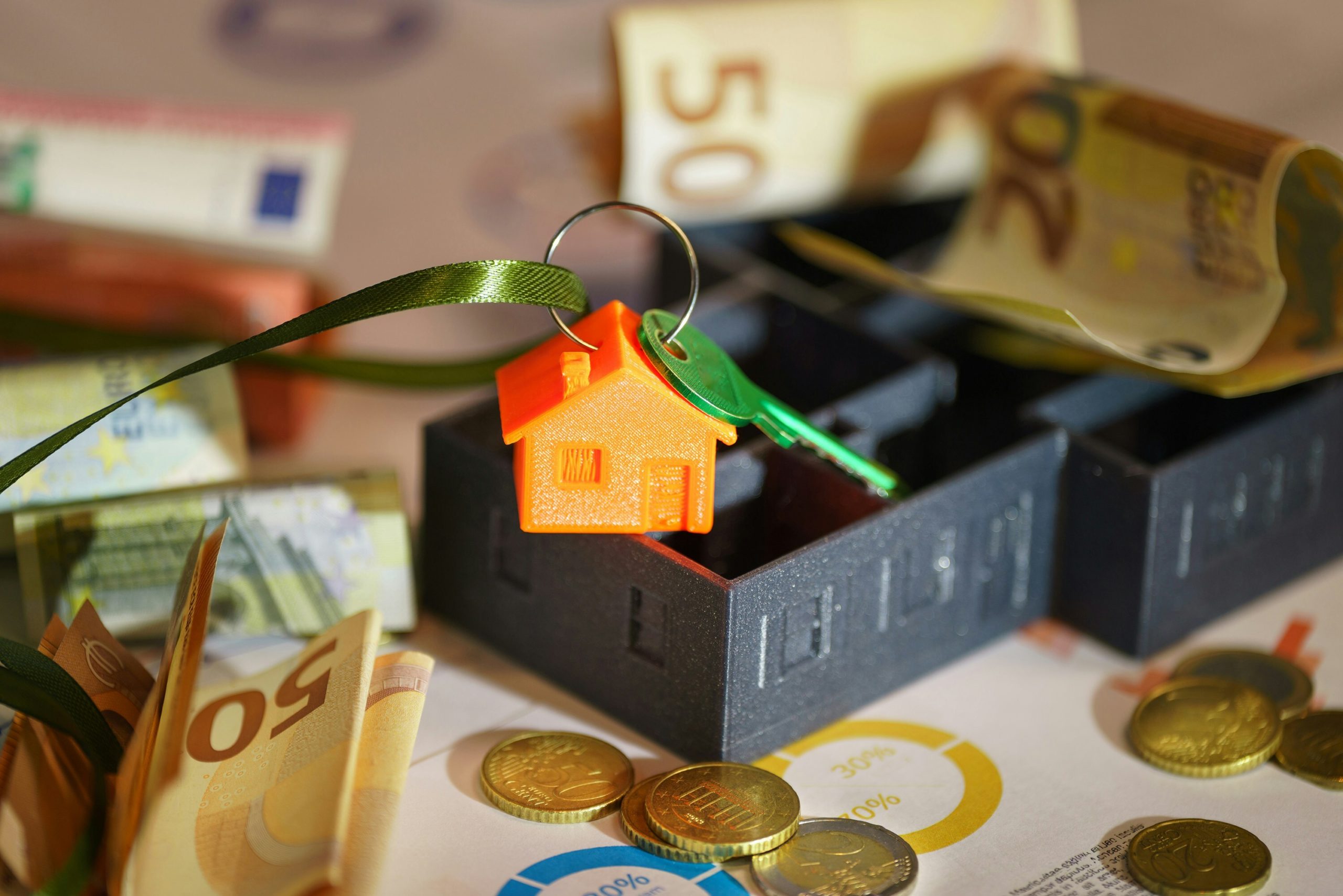 Money and a house key over financial charts, symbolizing school facilities planning and budget management